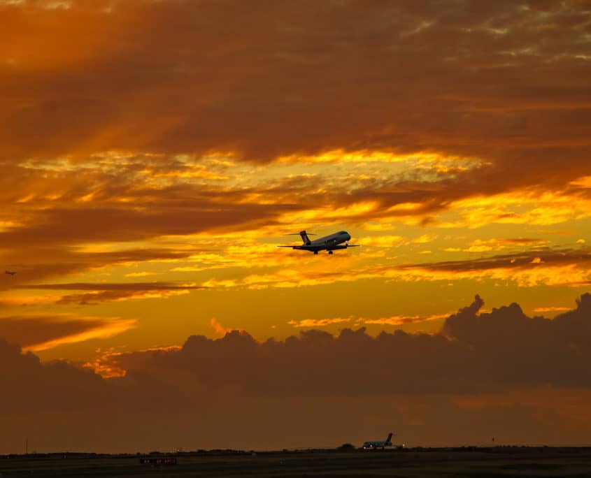 Plane Flying into Sunset with clouds